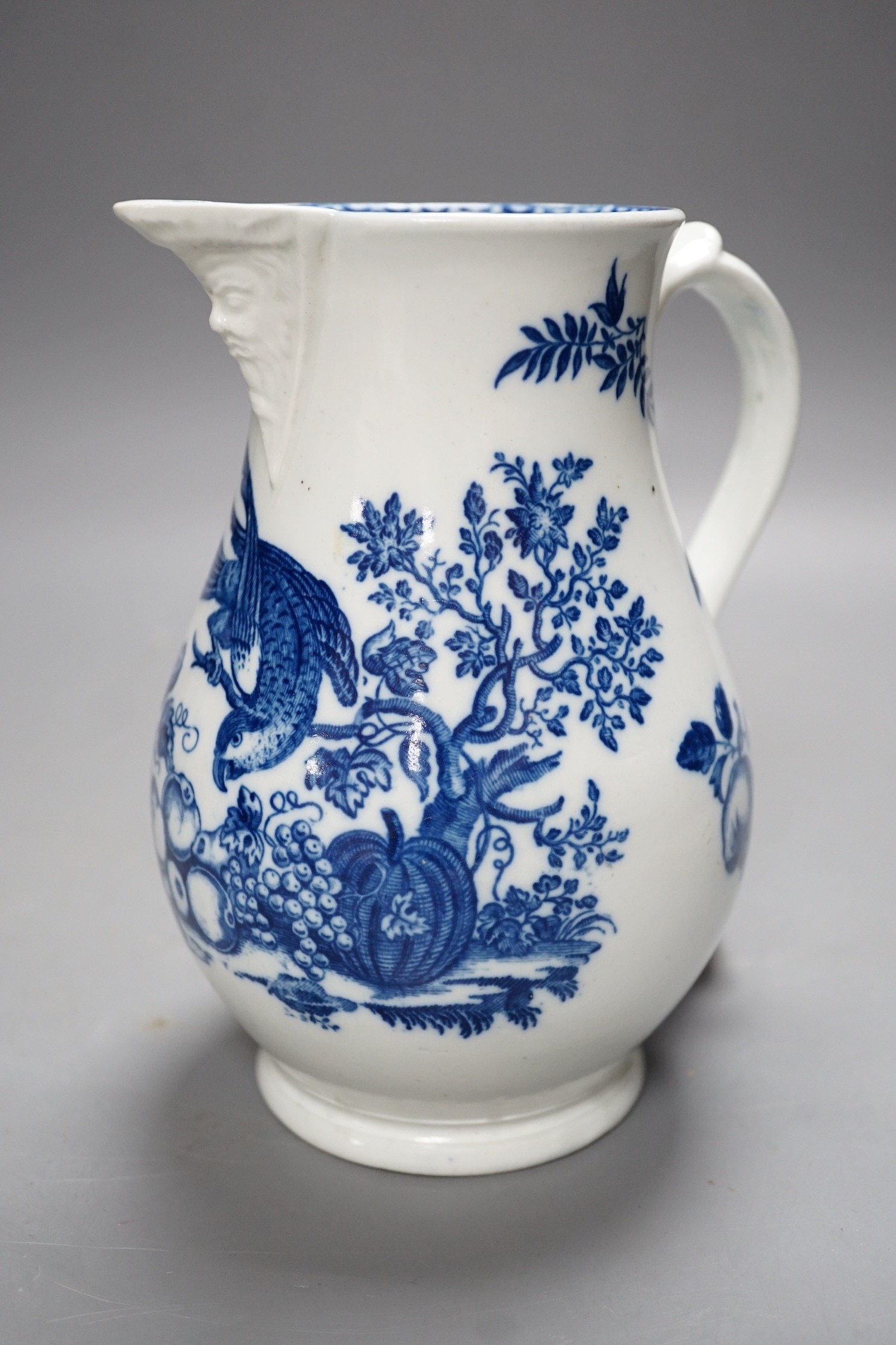 A Caughley baluster mask jug printed in underglaze blue with the 'parrot pecking fruit', 18.5cms high